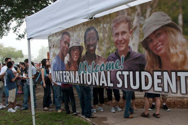 A sign welcomes international students as they stand in line for a household goods giveaway