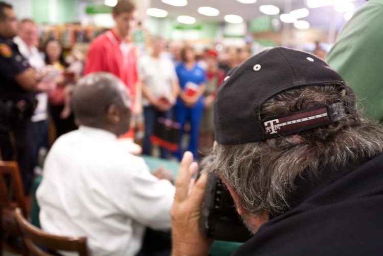 A newspaper photographer focuses on Herman Cain at a book signing
