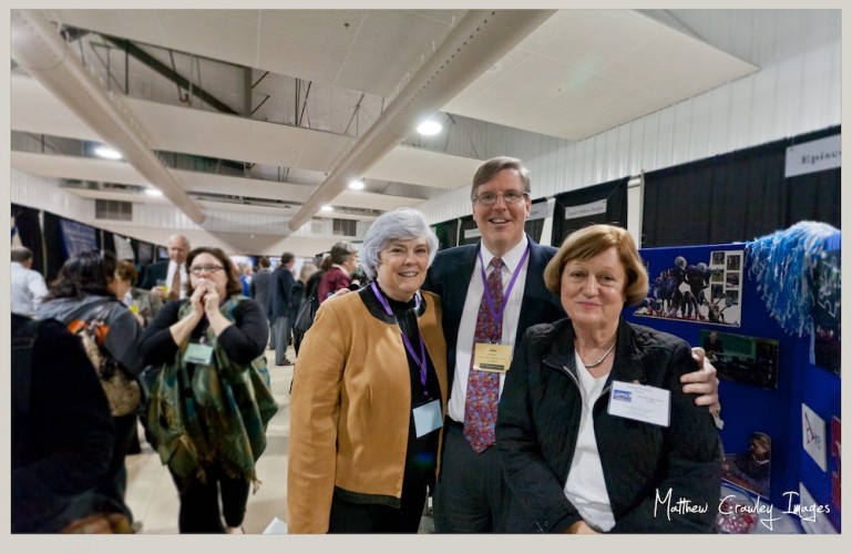A man and two women pose in an exhibit hall