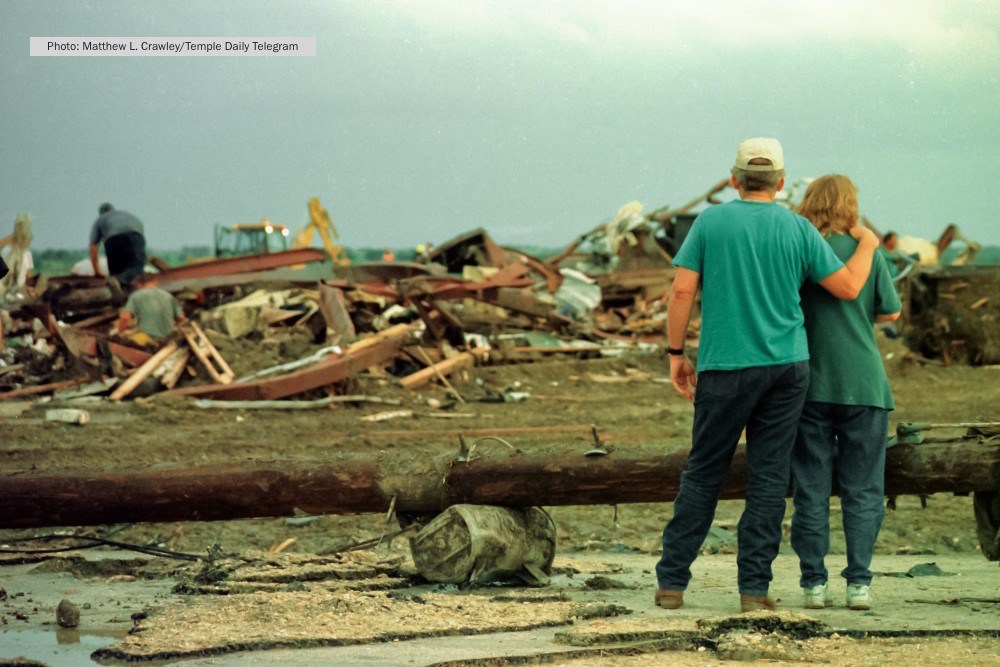 An unidentified couple watches as volunteers and rescue workers dig through the debris of a recycling facility in Jarrell, Texas. The plant was destroyed by a tornado on May 27, 1997. © Temple Daily Telegram/Matthew Crawley
